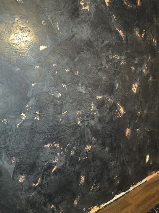 Close-up of charcoal Venetian plaster with copper leaf flecks